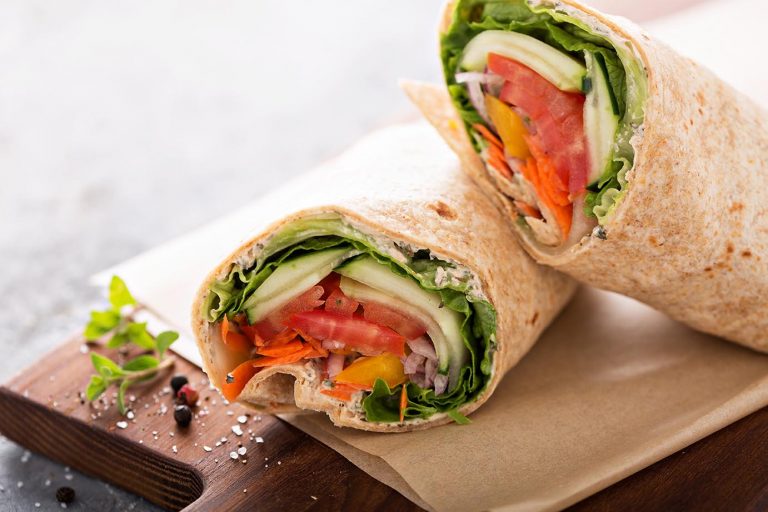 Vegan vegetable wrap with lettuce, cucumber and tomatoes sliced in half